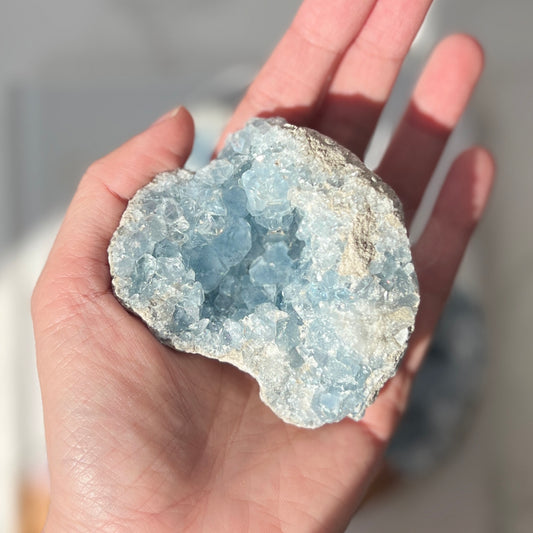 A hand holding a polished blue celestite cluster.